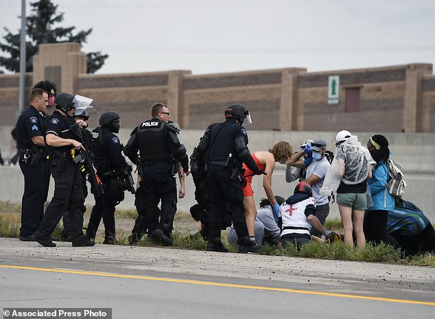 Aurora Police officers and volunteer medics tend to a protester who was shot and wounded when a suspect identified as Young opened fire on the highway on Saturday