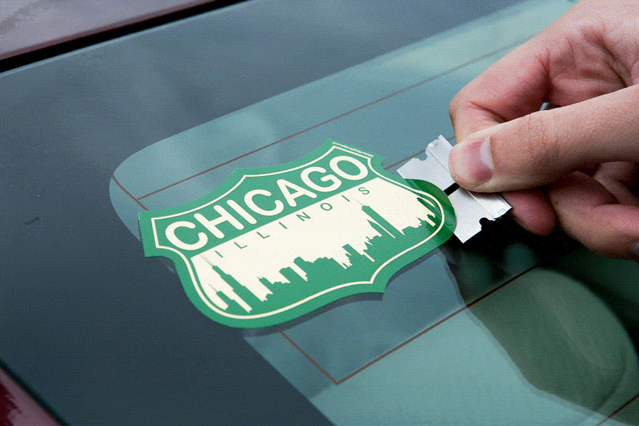 Using a razor blade to remove a sticker from a car